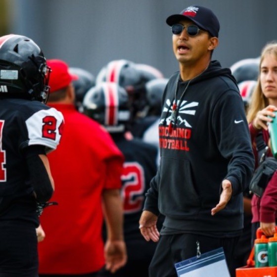 Cristo Tabares coaching football players on the sideline